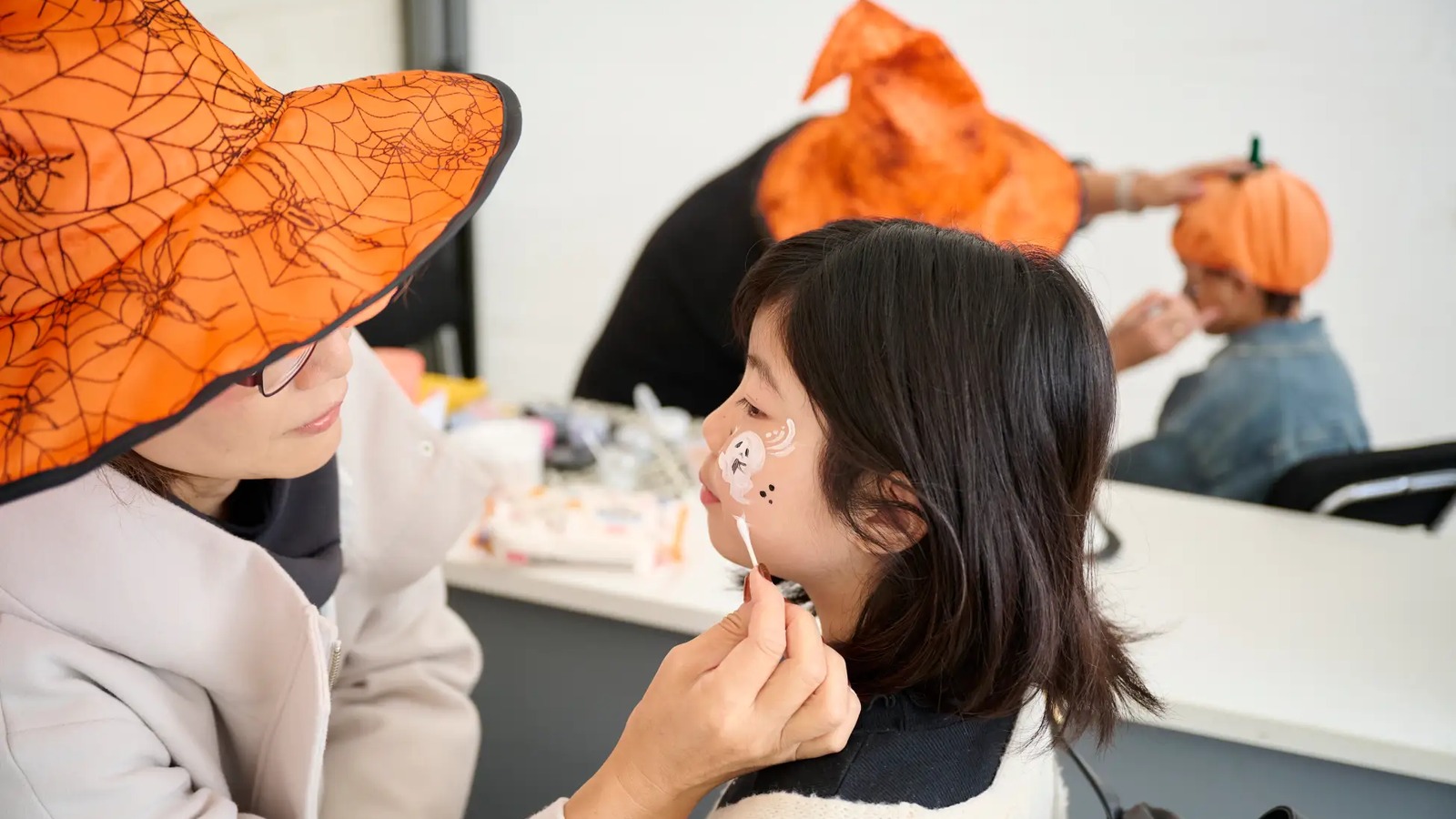 ハロウィンのフェイスペイントを受ける子ども